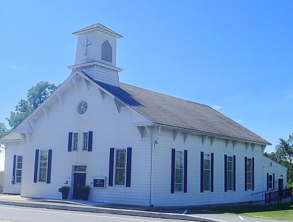 A white church with a clock tower and black shutters