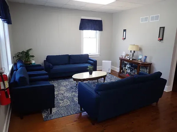 A living room with blue couches and chairs and a coffee table.