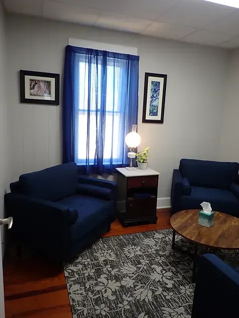A living room with two blue chairs and a round coffee table