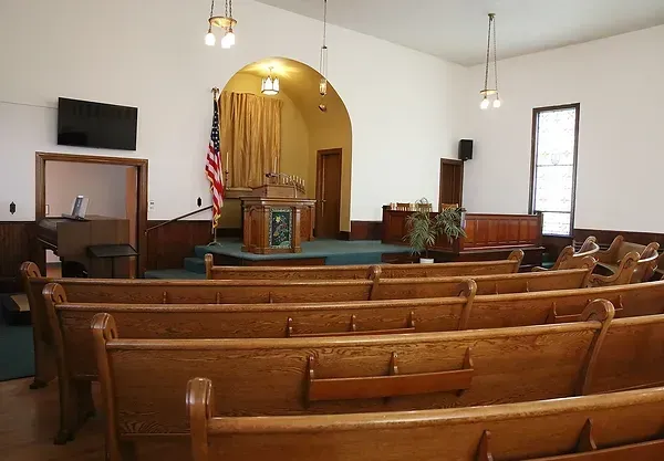 An empty church with wooden benches and a podium