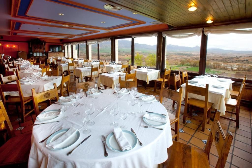 Un restaurante con mesas y sillas y vista a las montañas.