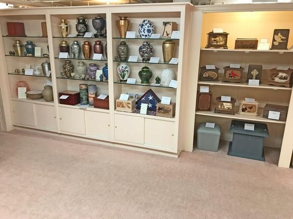 Display shelves filled with various funeral urns and memorial keepsakes in a funeral home showroom.