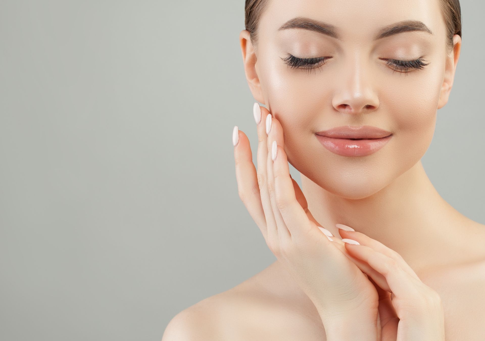 closeup of young female model with lip filler holding her hands under chin