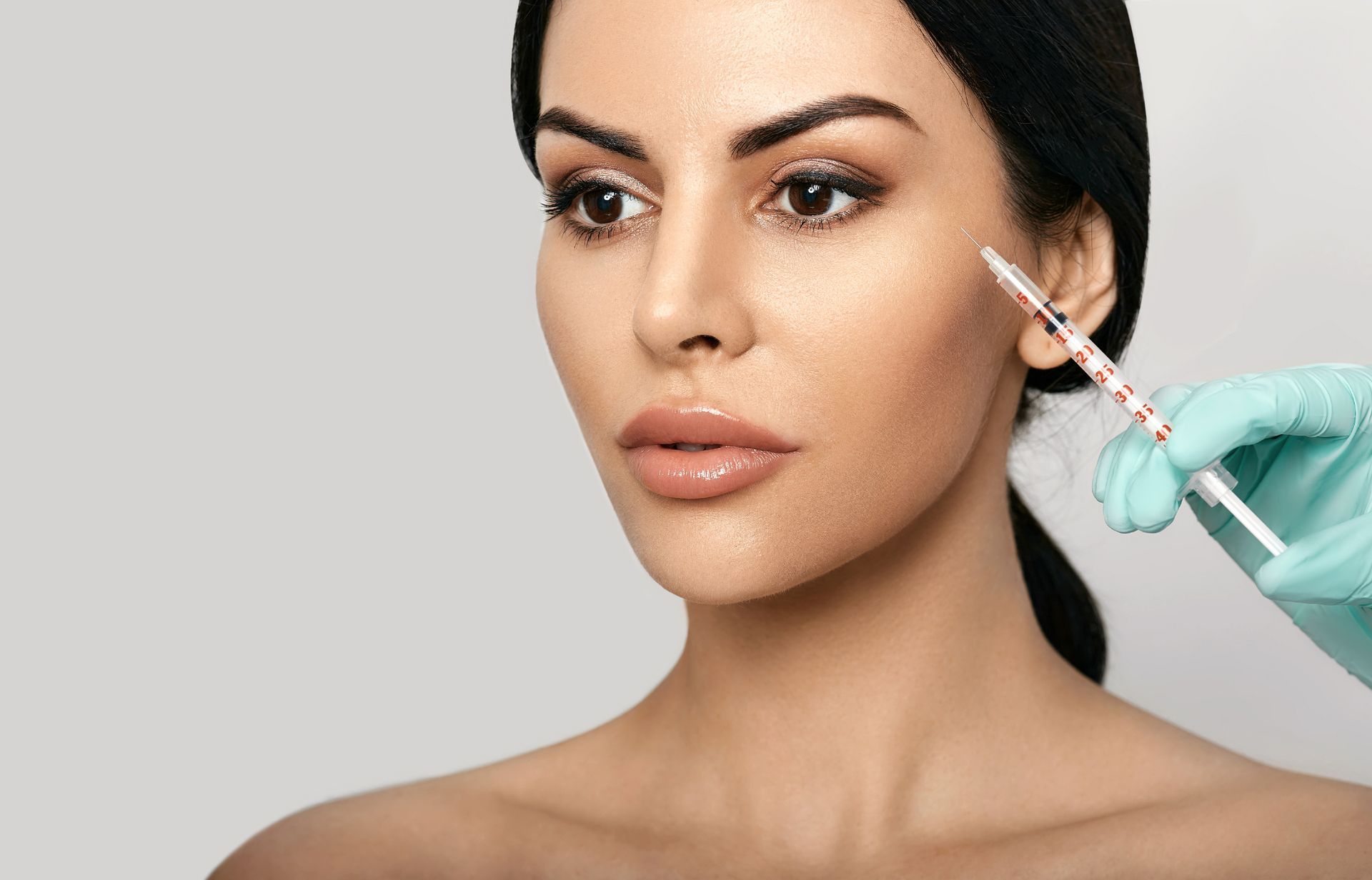 glamorous woman in her 40s receives beauty injection in crows feet area