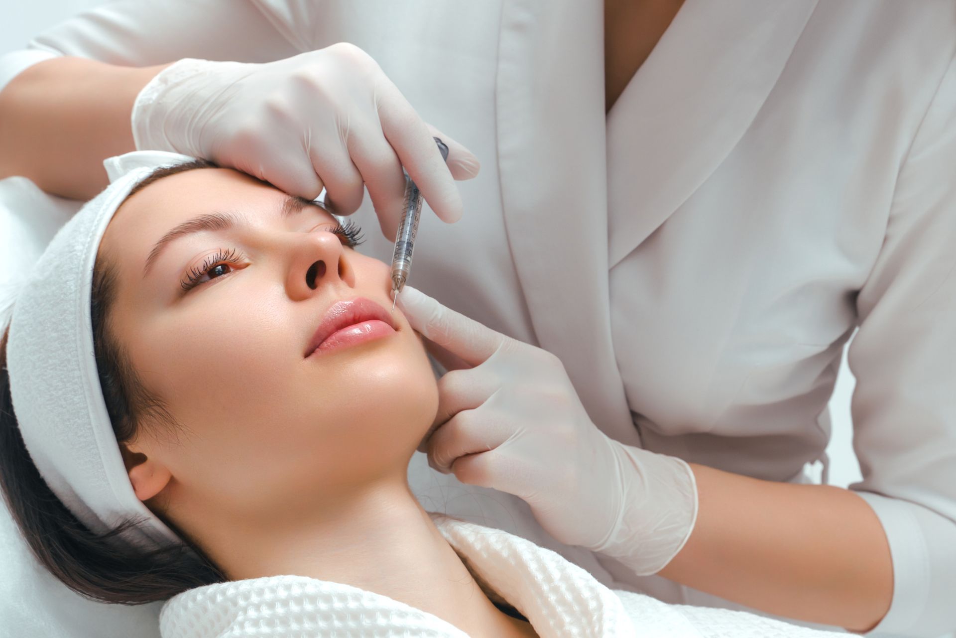 doctor injects female patient's cheek area with biostimulant