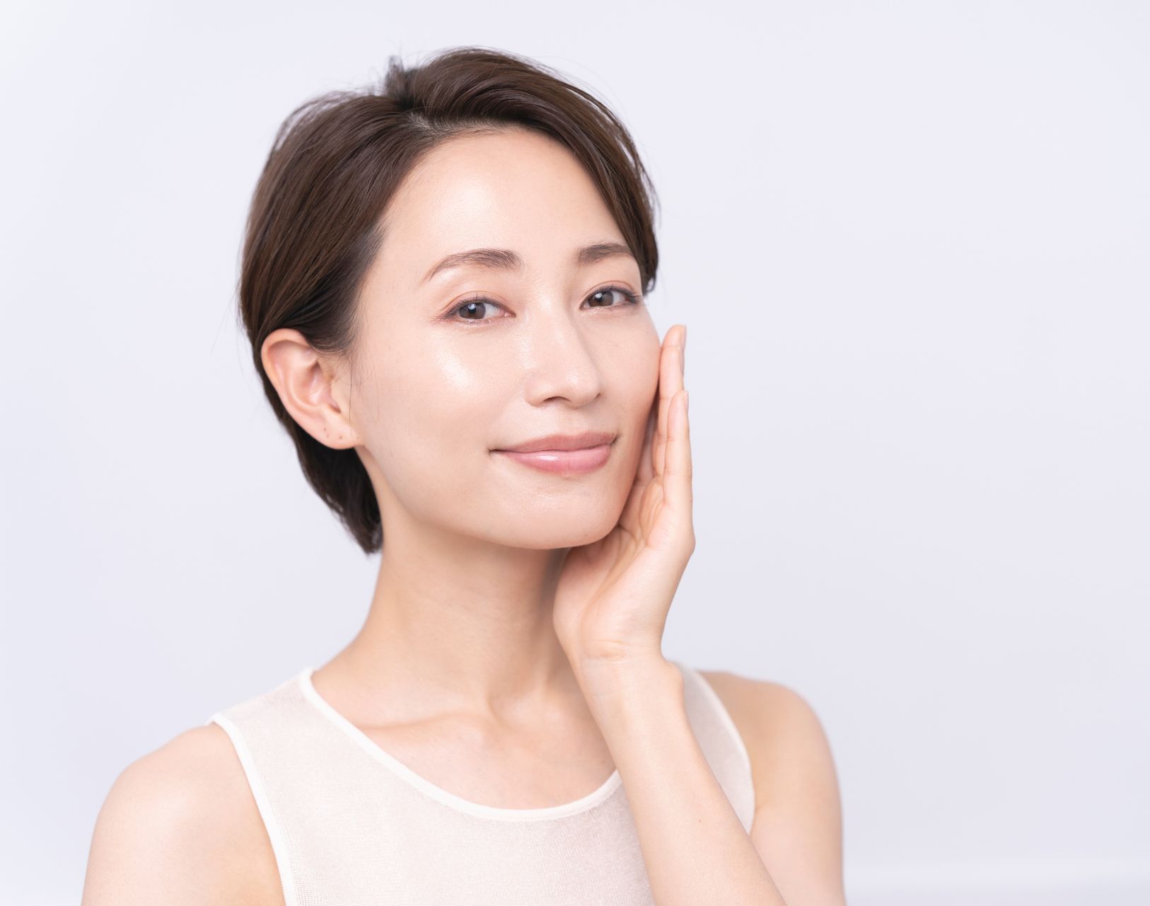 mature asian woman with glowing skin holding one hand on her face