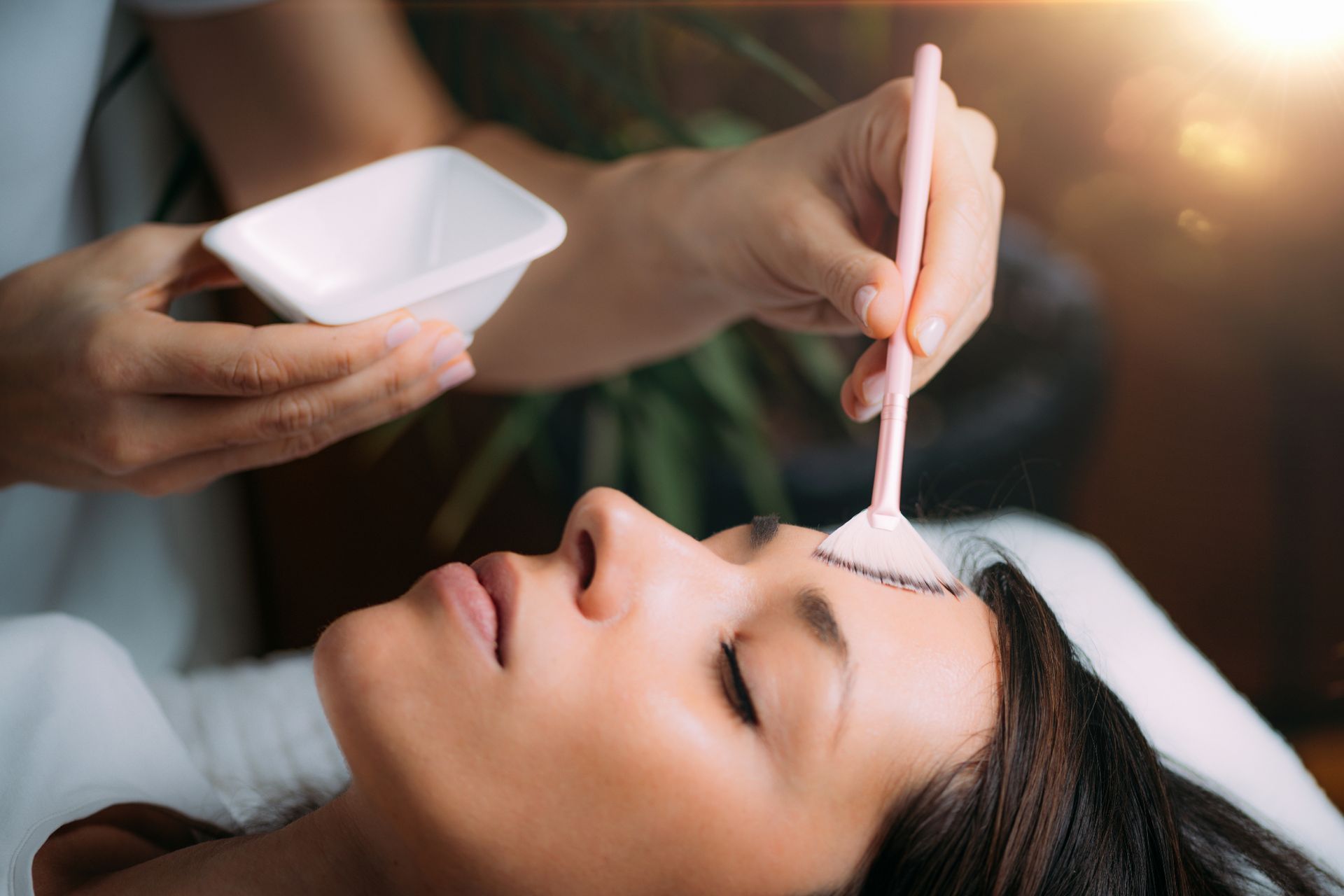 closeup of dermatologist brushing chemical peel treatment onto female patient's forehead