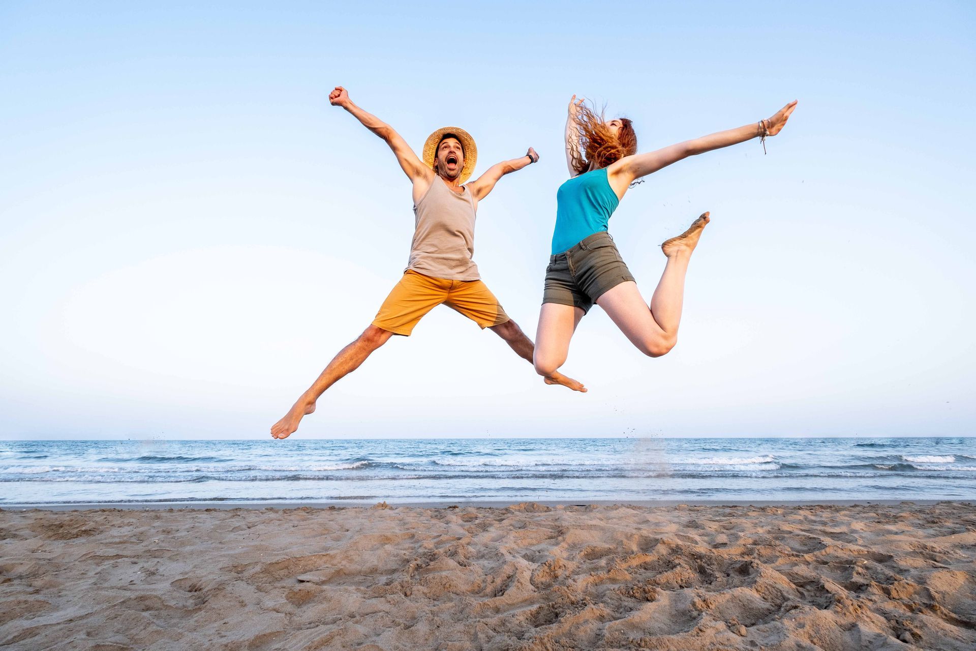 happy couple jumping in the air at the beach