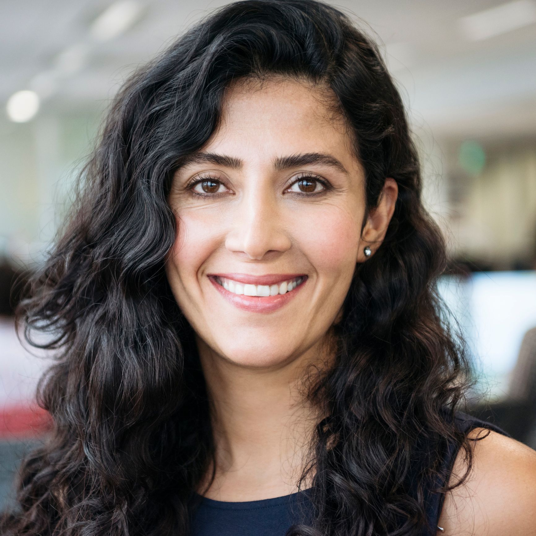 A Woman With Long Curly Hair Is Smiling For The Camera – Terrigal, NSW - Anjule Beauty Therapy