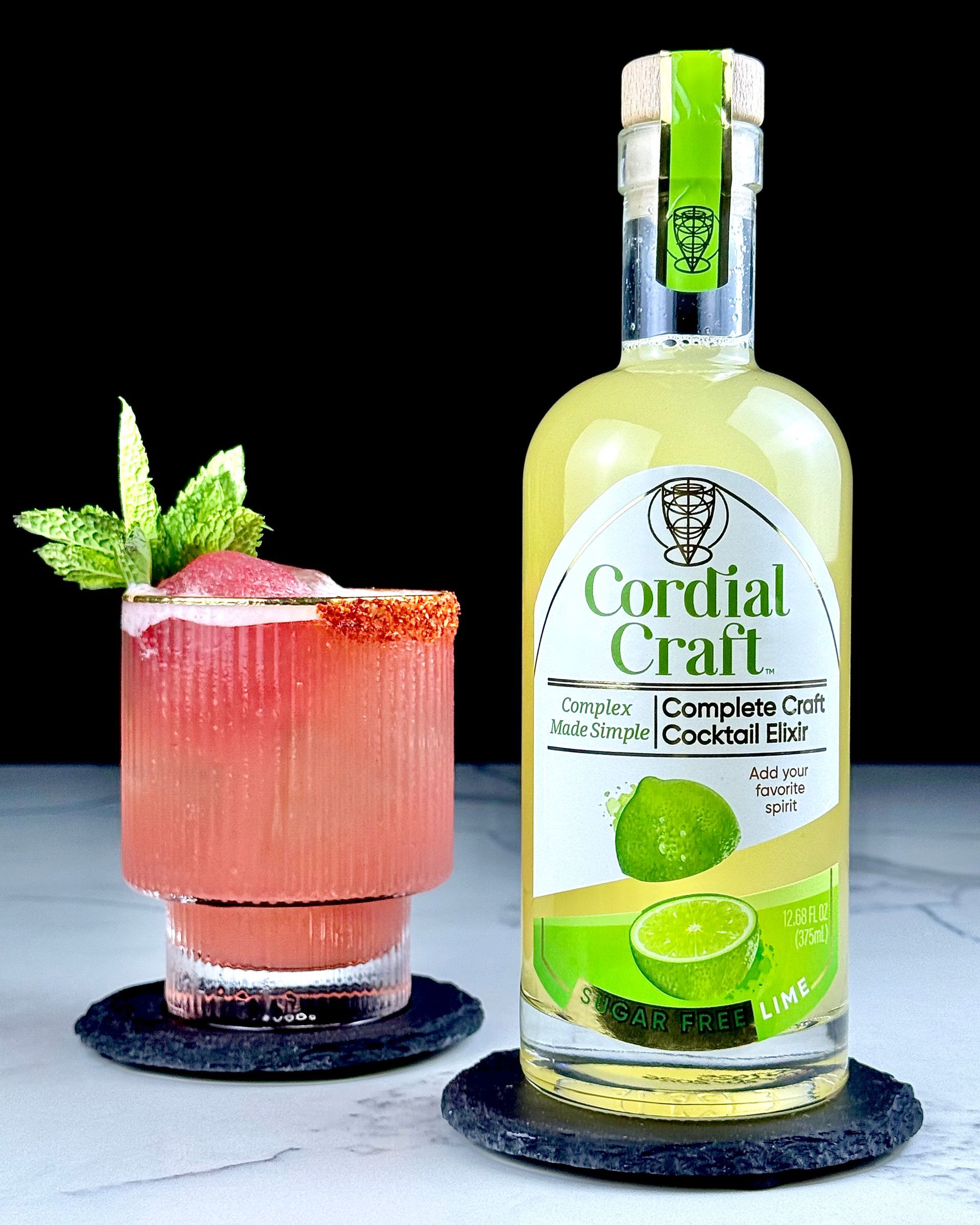 Cocktail in a glass with a Tajin rim, next to a bottle of Cordial Craft lime cordial.