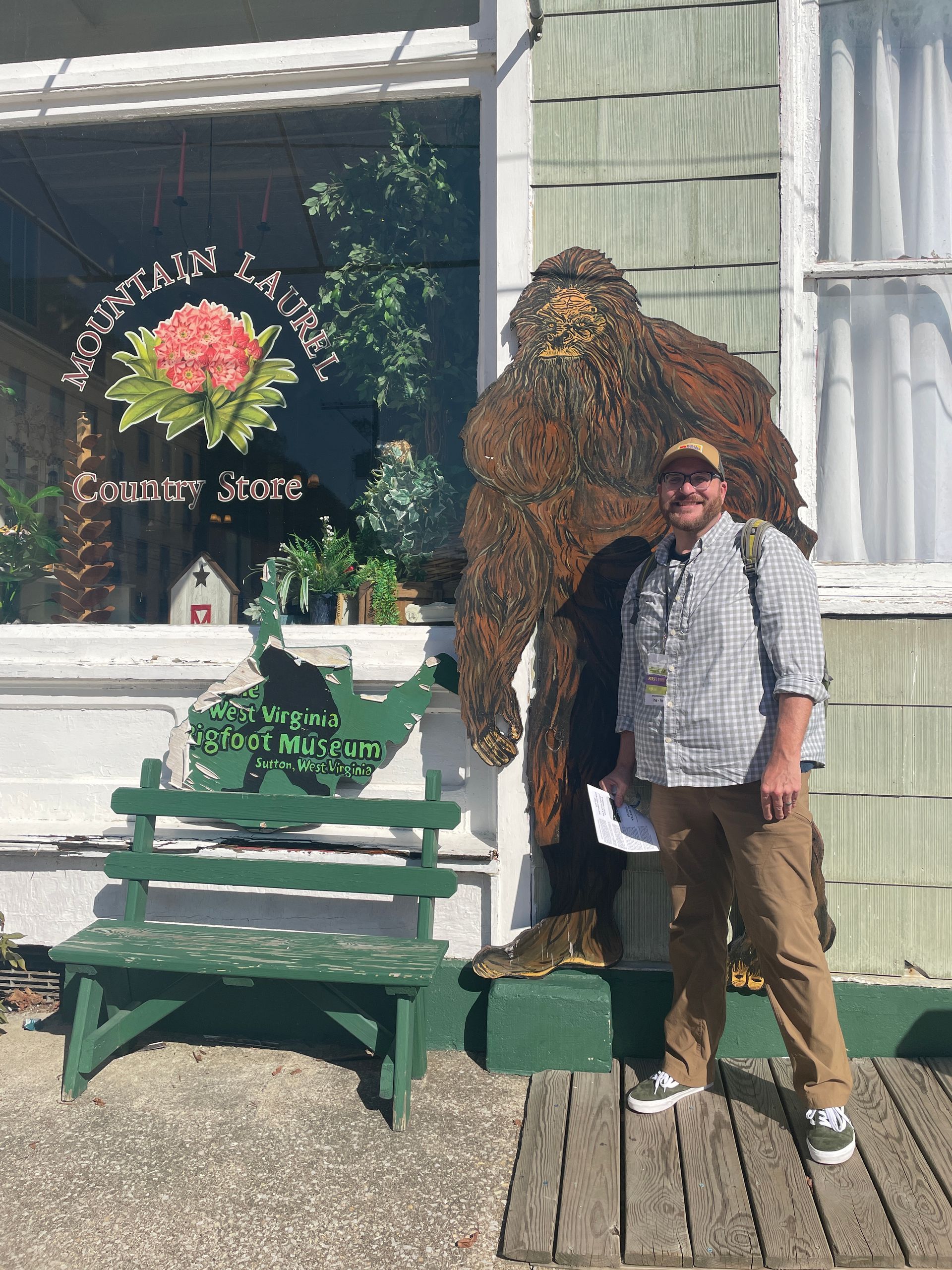 A person stands on a wooden porch beside a large Sasquatch outside the Mountain Laurel Country Store.