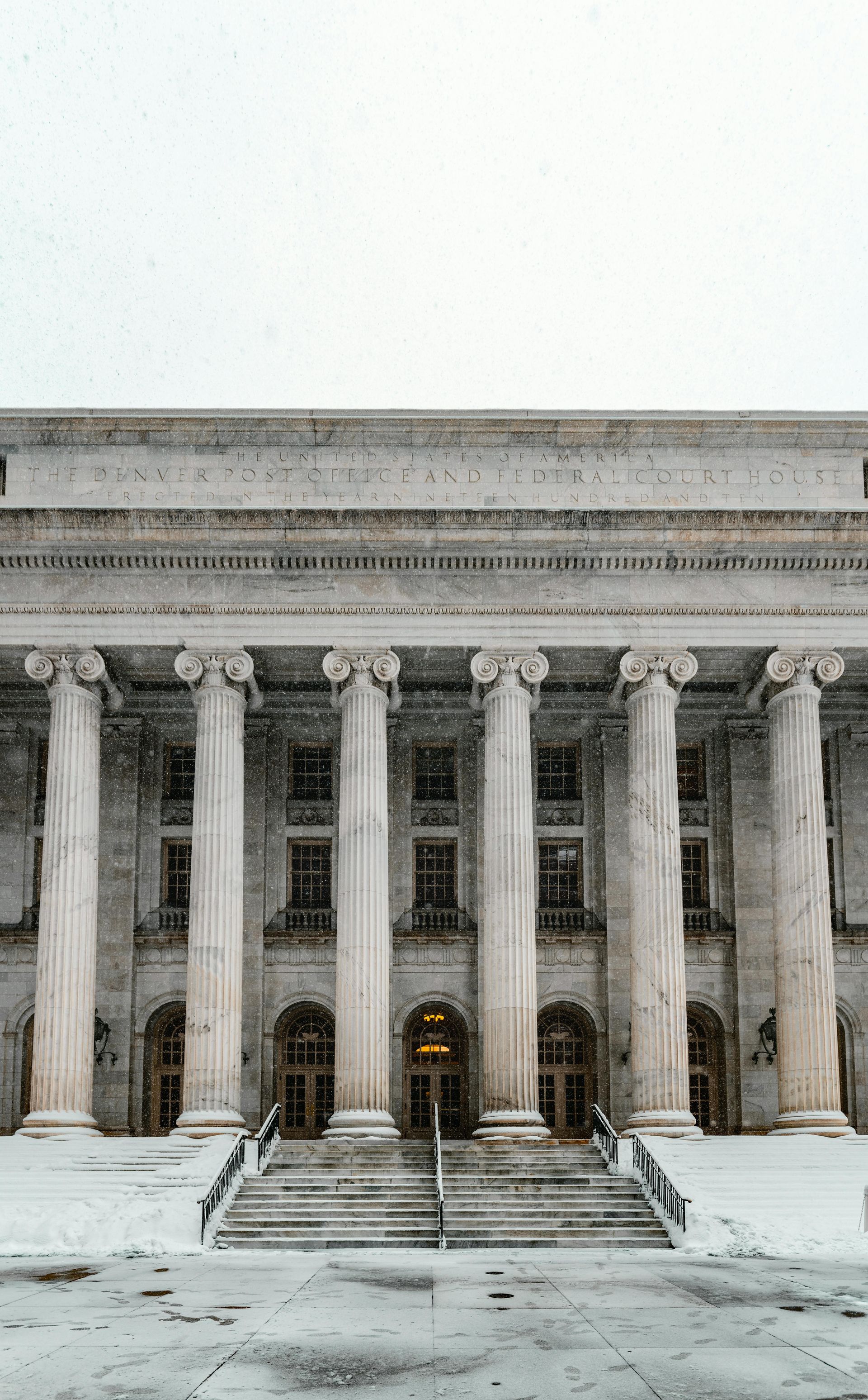 Snowy courthouse facade with large columns and steps leading to the entrance.