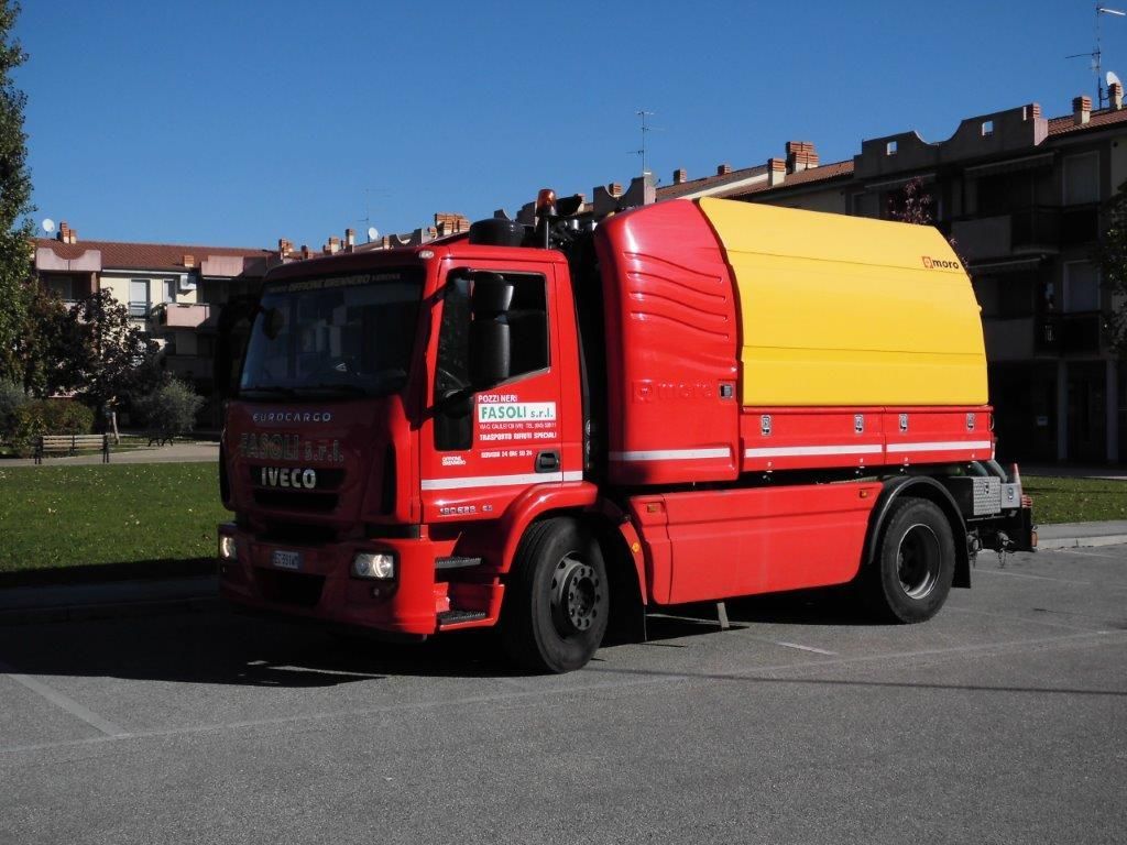 Un camion Iveco rosso e giallo è parcheggiato sul ciglio della strada