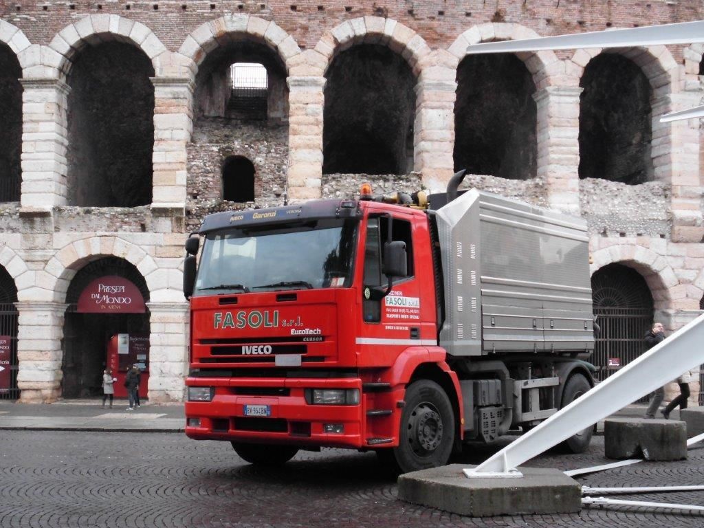 Un camion Iveco rosso è parcheggiato davanti a un edificio