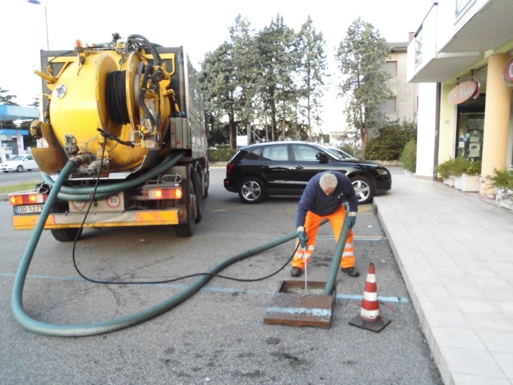 Un uomo sta lavorando su un tombino accanto a un camion giallo