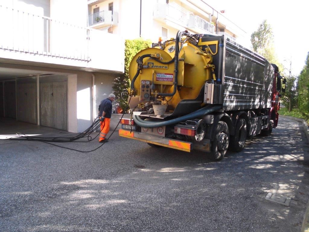Un uomo è in piedi accanto a un camion della spazzatura sul ciglio della strada.