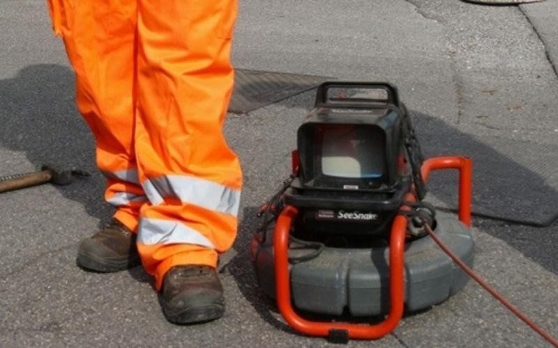 Un uomo con pantaloni arancioni è in piedi accanto a una telecamera