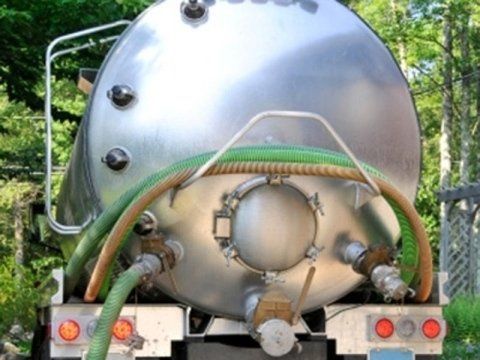Un grande serbatoio in acciaio inossidabile con un tubo verde attaccato.