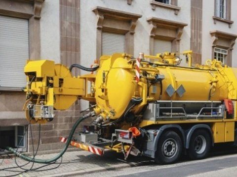 Un camion giallo per la pulizia degli ambienti è parcheggiato davanti a un edificio.