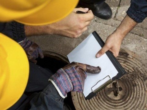 Un uomo sta scrivendo su un blocco per appunti davanti a un tombino