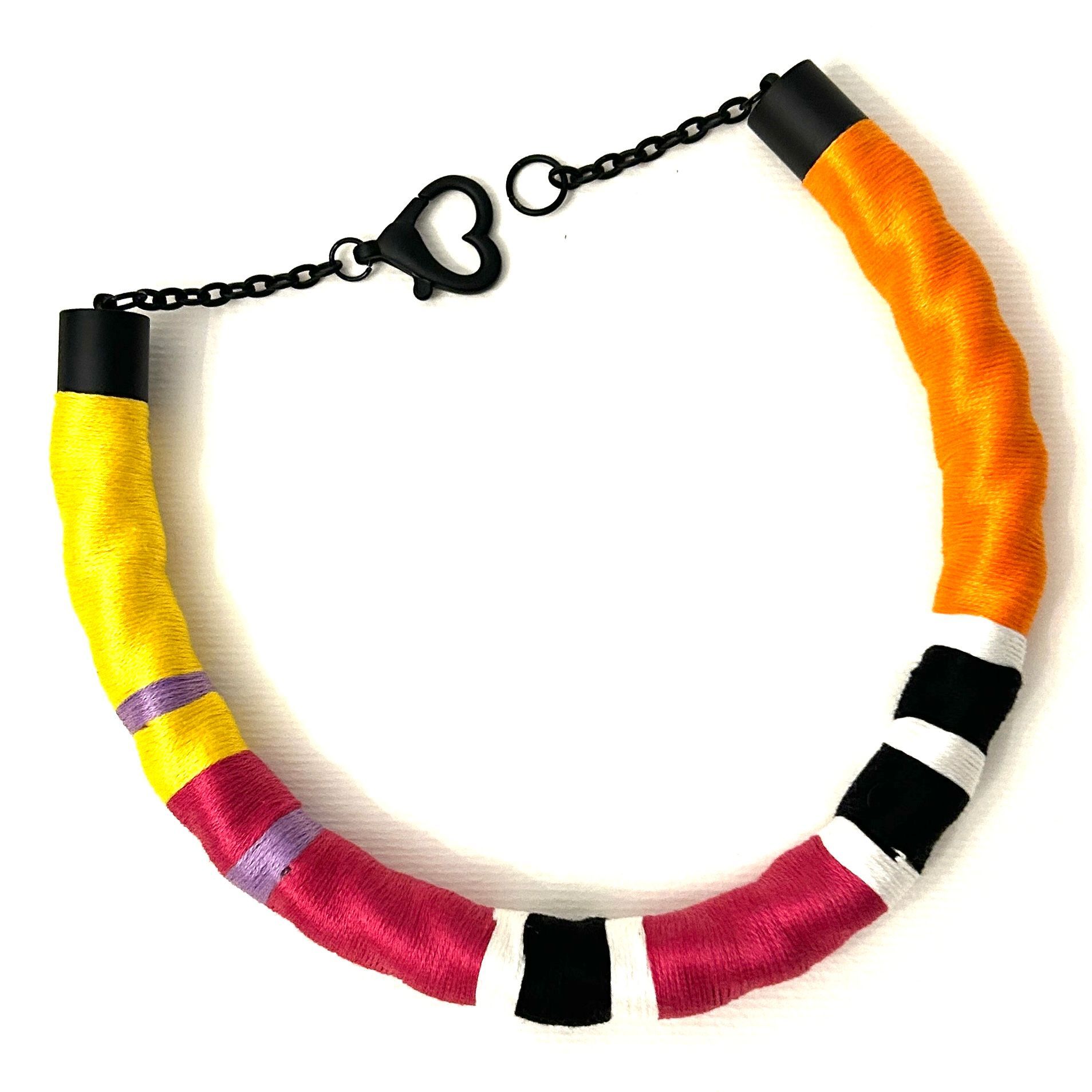 Un collar colorido con un cierre negro sobre un fondo blanco.