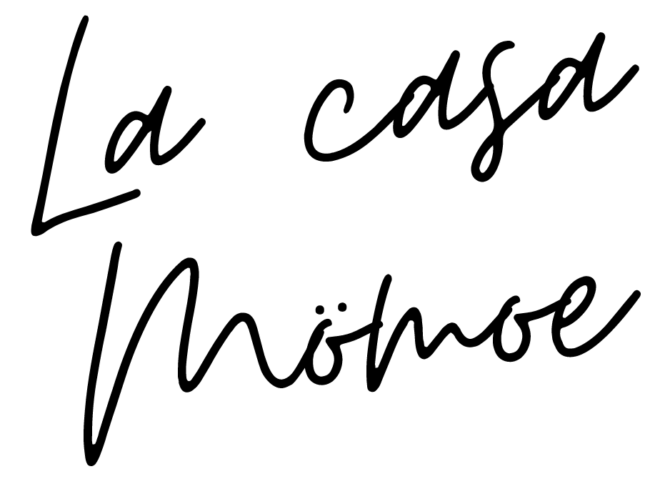 Un logotipo escrito a mano en blanco y negro para La Casa Momoe.