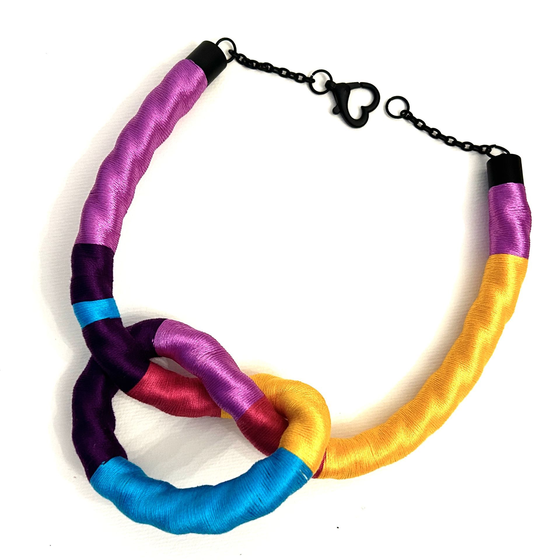 Un collar colorido con un cierre negro sobre un fondo blanco.