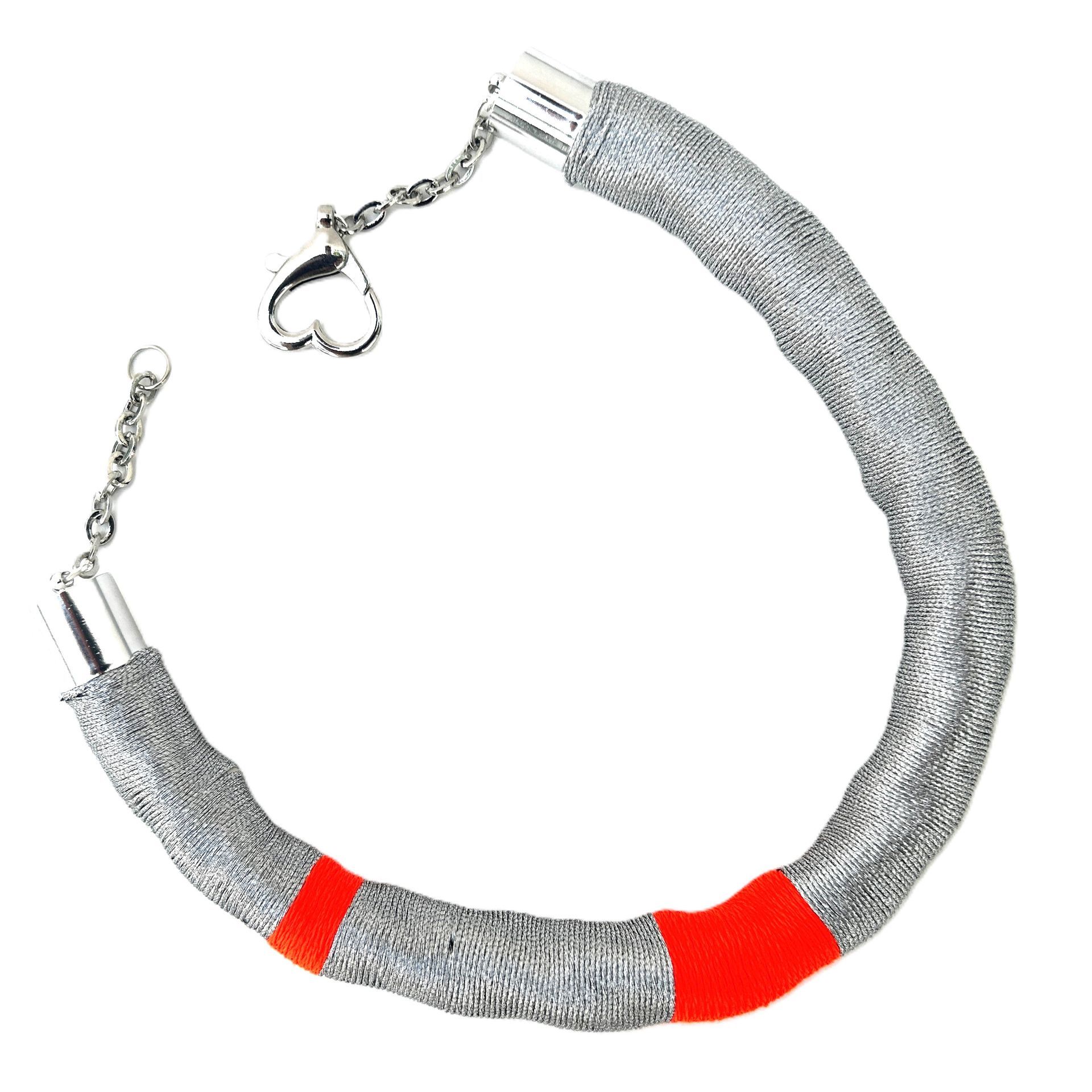 Una pulsera de plata y roja con un cierre en forma de corazón.