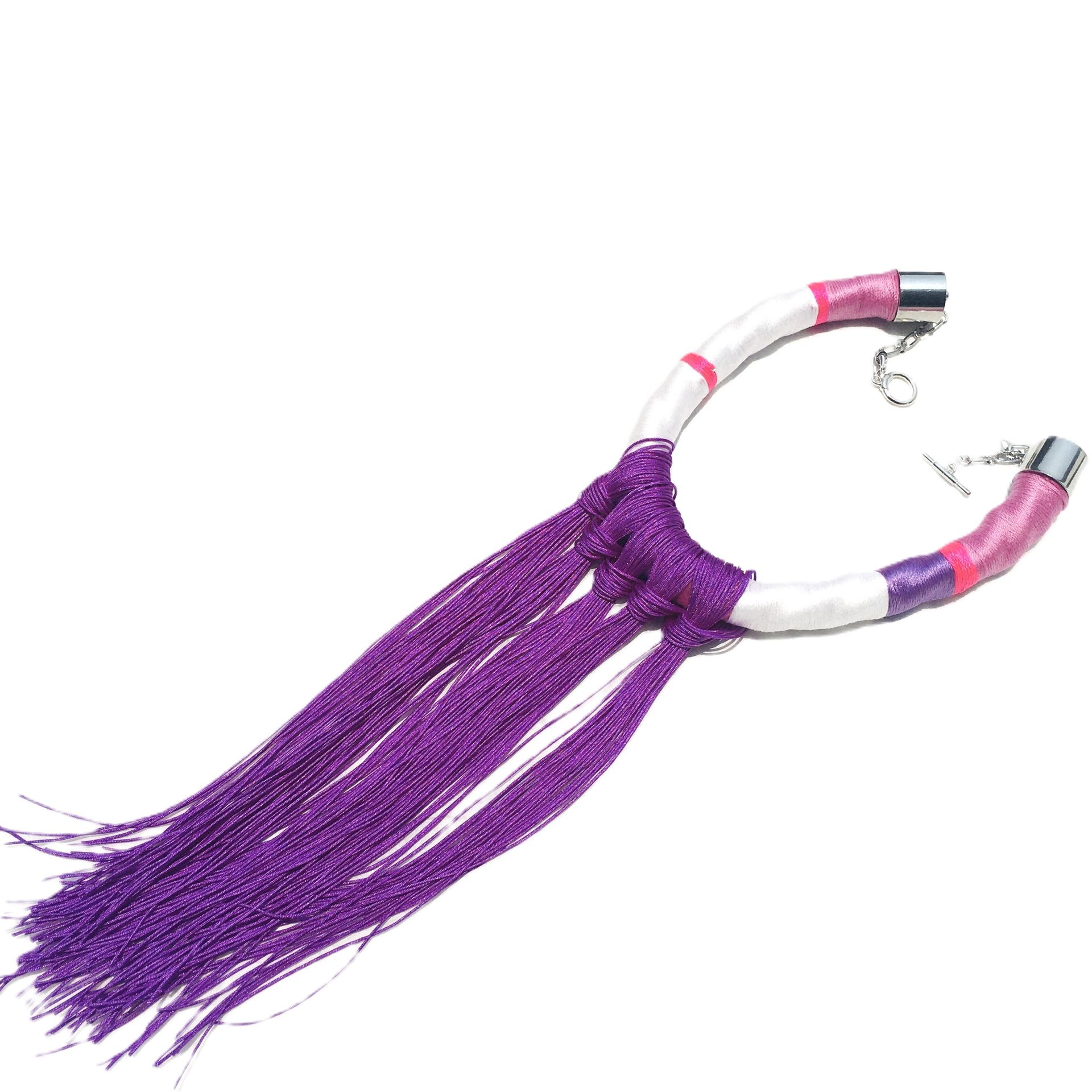 Un collar morado y blanco con flecos sobre un fondo blanco.