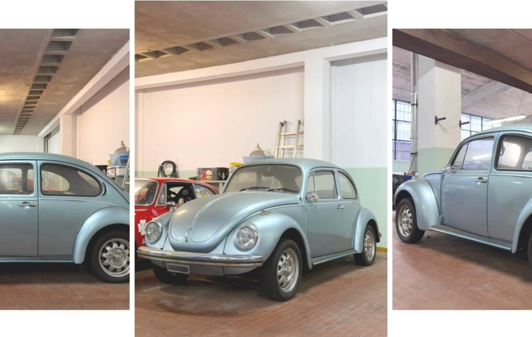 Tre immagini di un Maggiolino Volkswagen classico di colore azzurro chiaro in uno showroom simile a un garage.