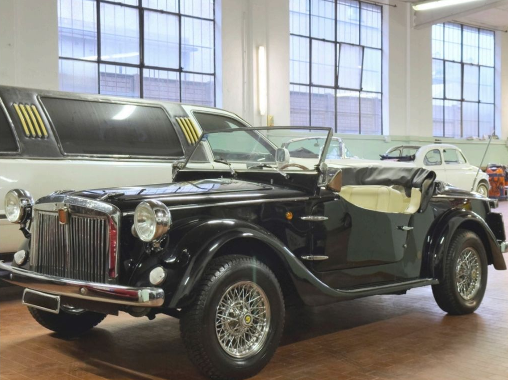 Auto decappottabile d'epoca nera esposta in uno showroom luminoso con ampie vetrate.