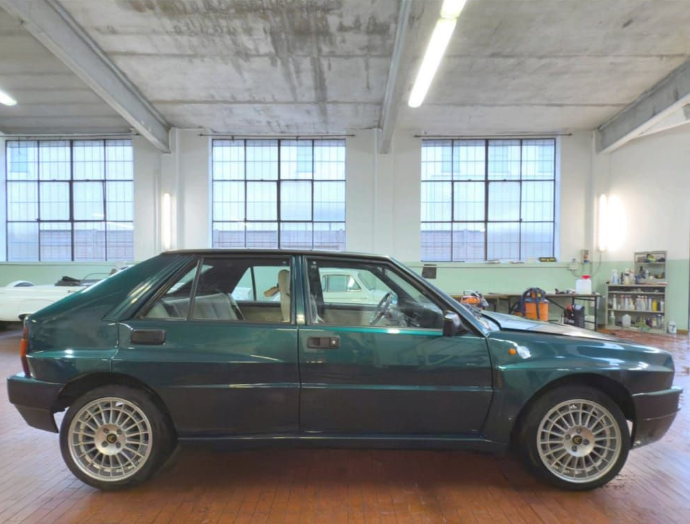 Auto hatchback verde scuro parcheggiata in un garage luminoso con grandi finestre