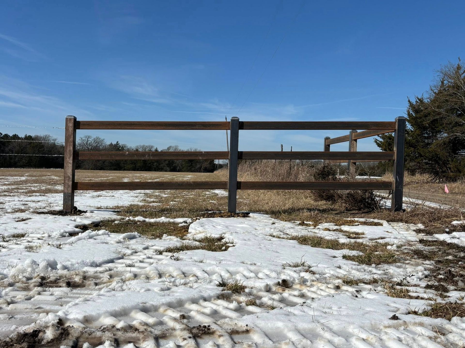 Snowy field with a wooden fence under a clear blue sky