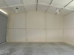Empty white metal garage interior with concrete floor and ceiling lights