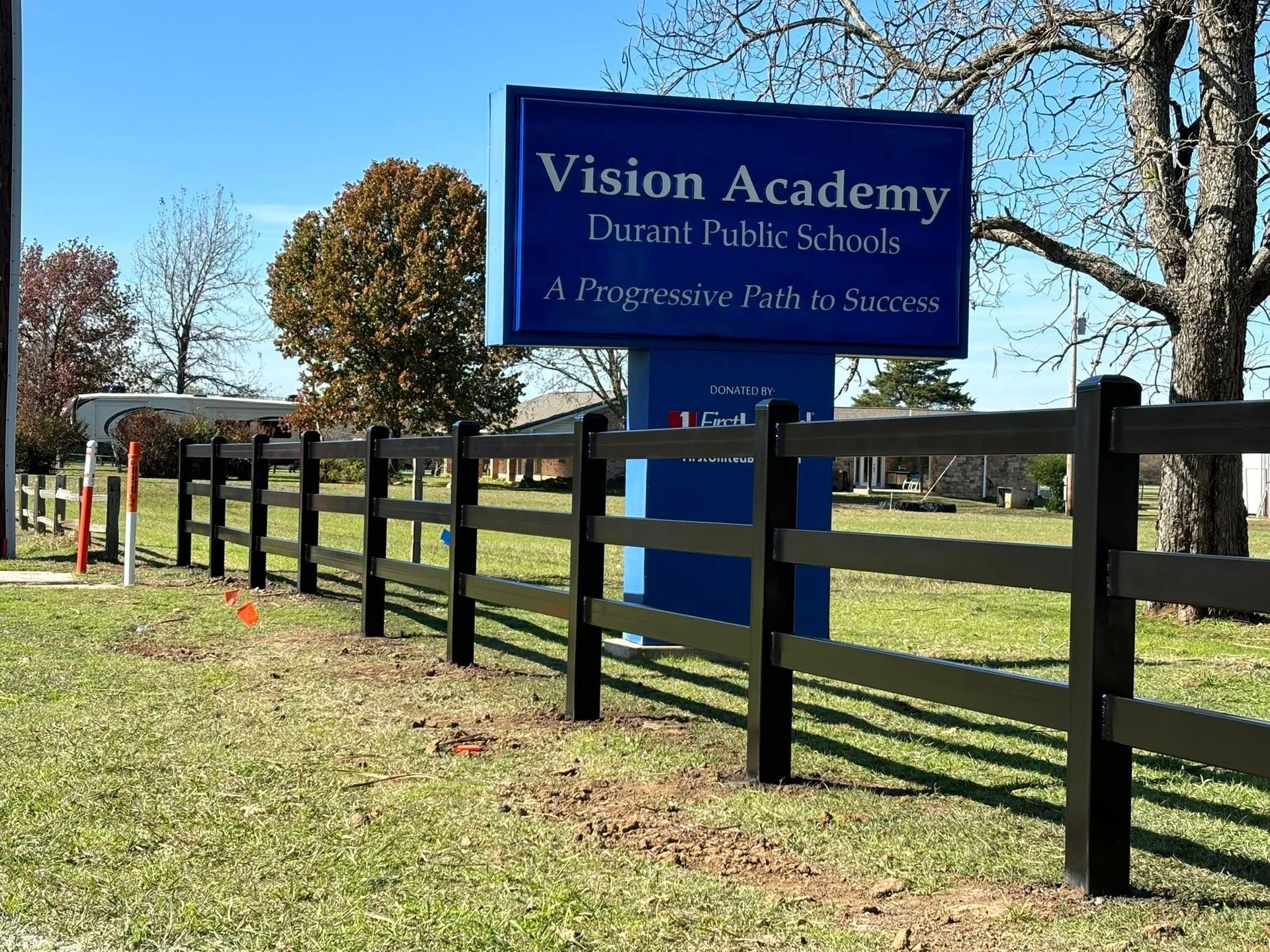 Vision Academy school sign beside a black wooden fence on a sunny day