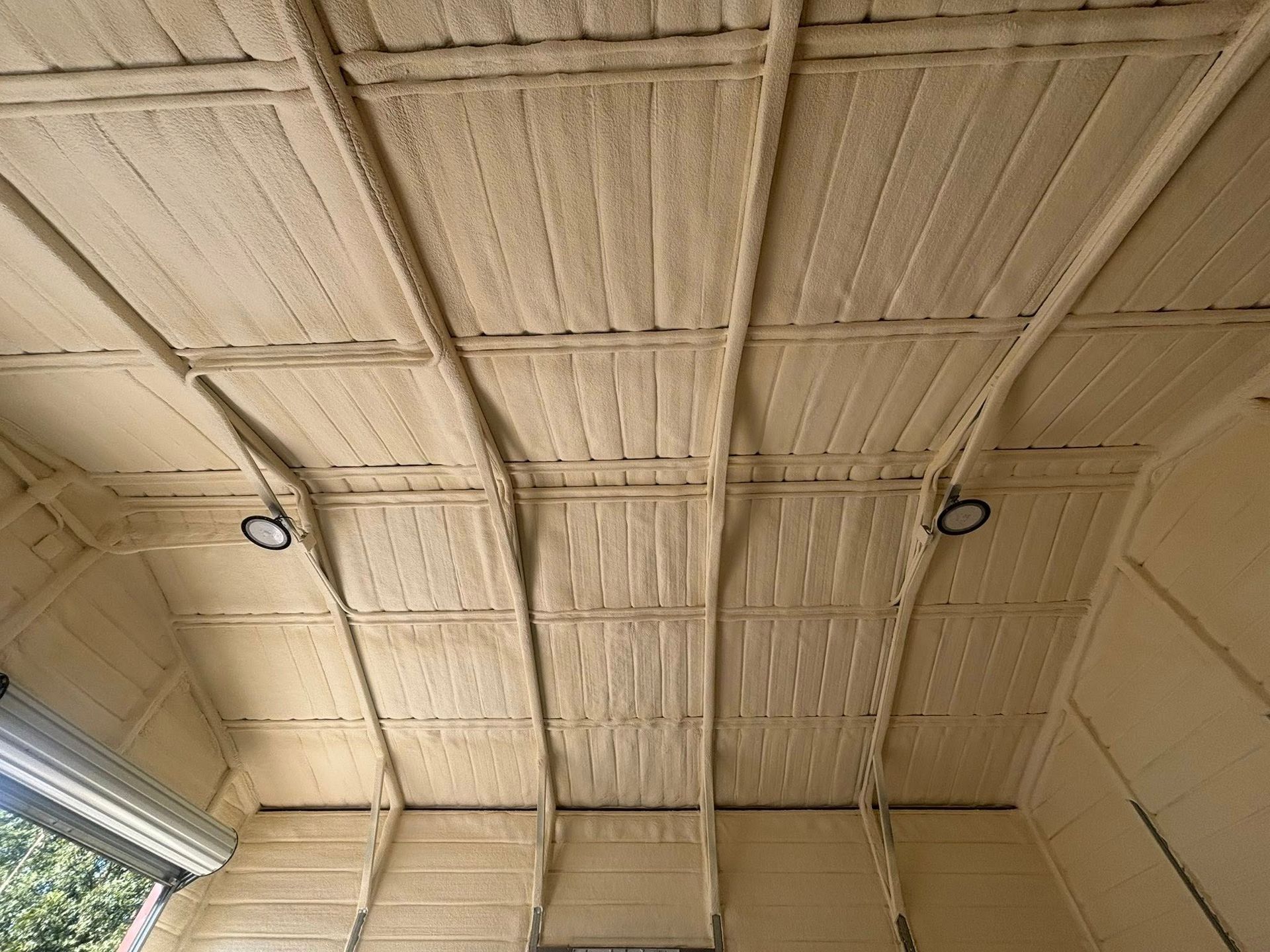 Curved beige industrial ceiling with exposed beams and two hanging light fixtures