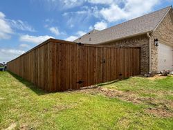 Wooden backyard shed beside a brick house on a grassy lawn under a partly cloudy sky