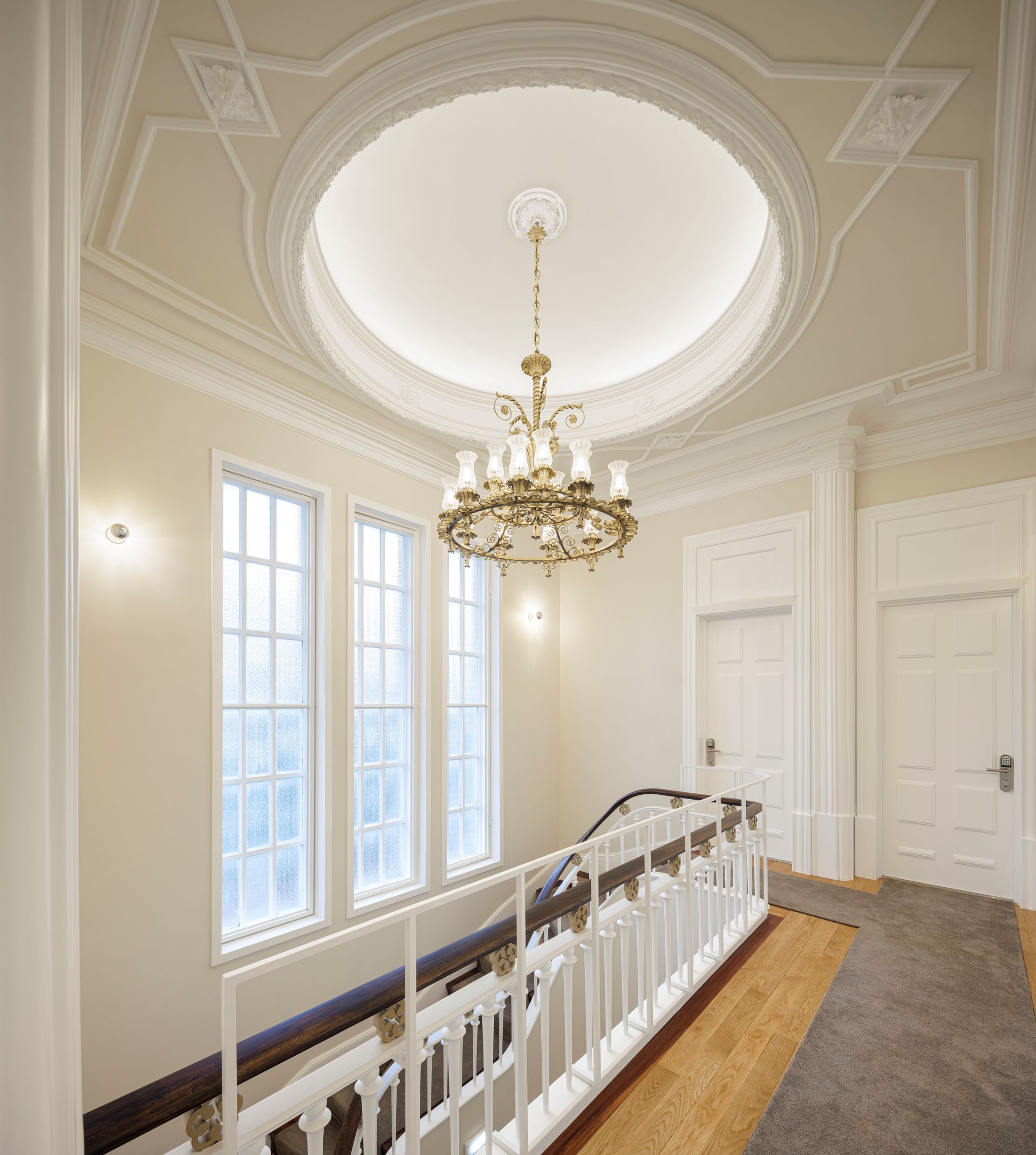 Casa Kala interior with high ceiling, ornate medallion, antique chandelier, and tall windows overlooking the stairwell.