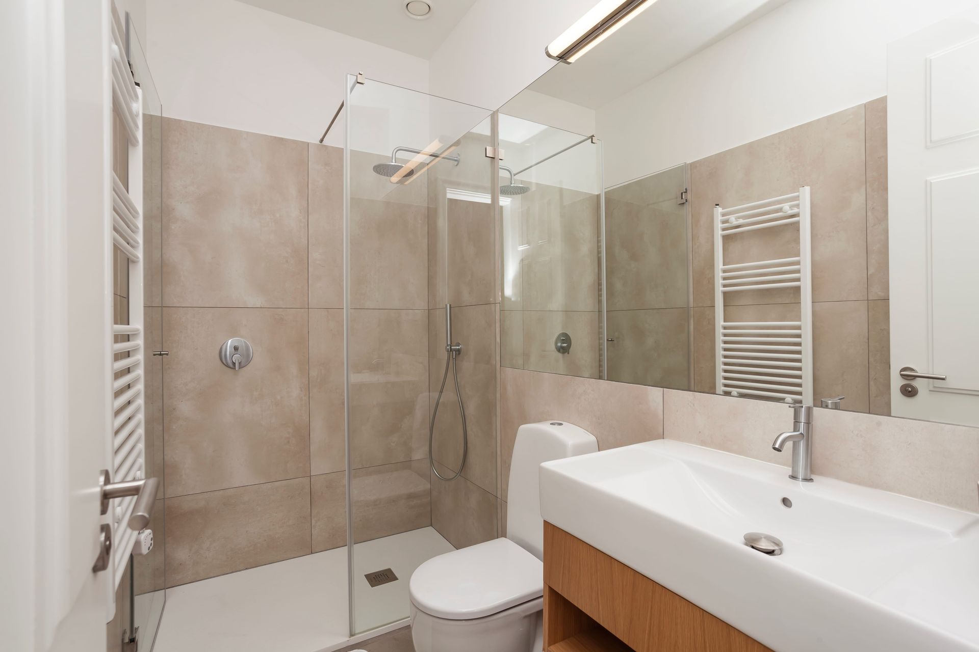 Private modern bathroom with large mirror and walk-in shower