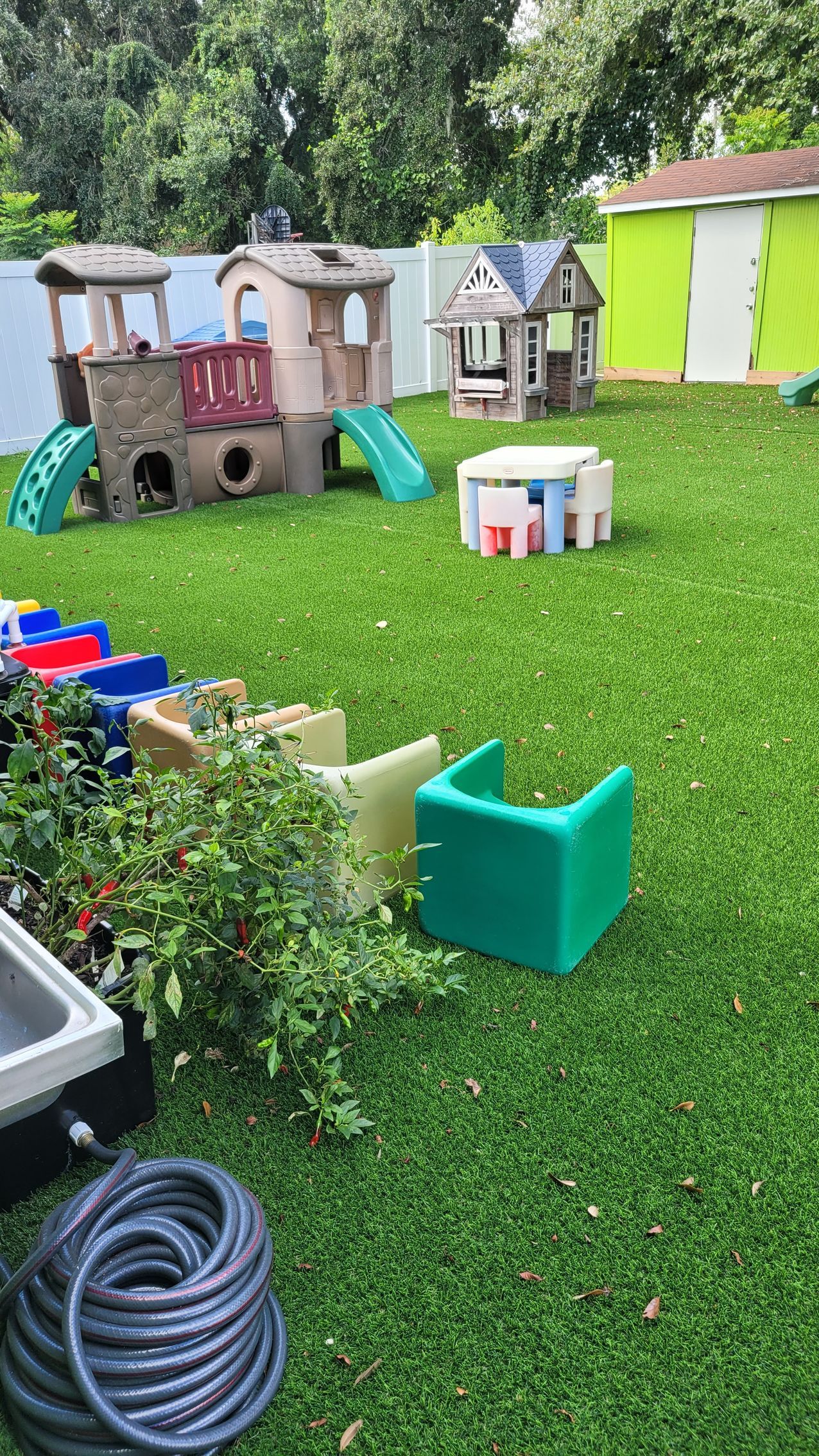 A backyard filled with lots of toys and a hose.