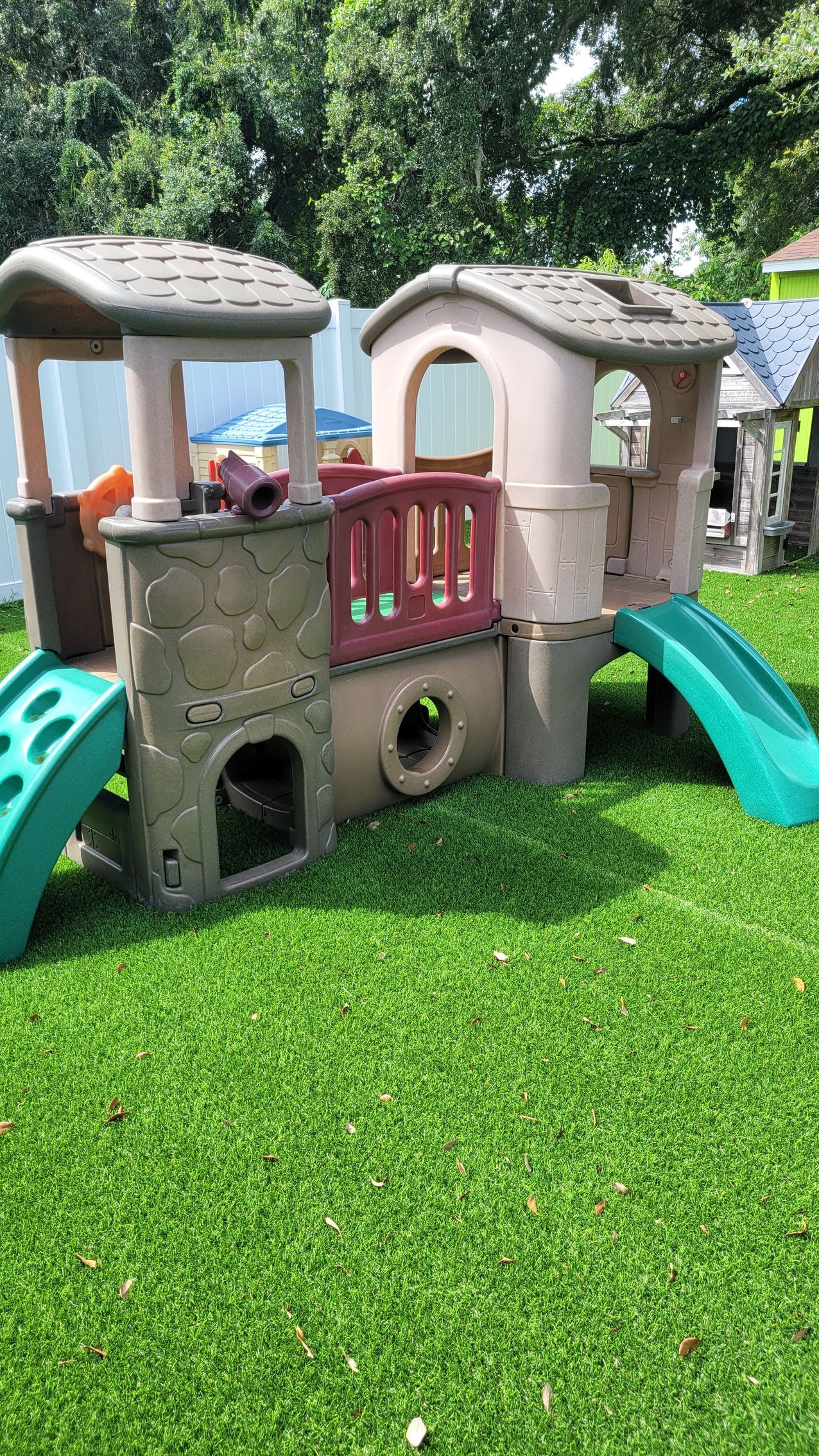 A playhouse with a slide and stairs is sitting on top of a lush green lawn.