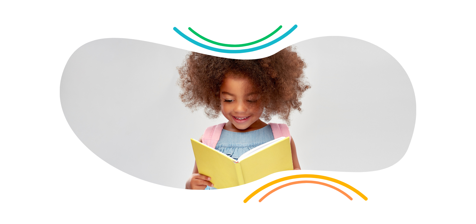 A little girl is reading a book and smiling.