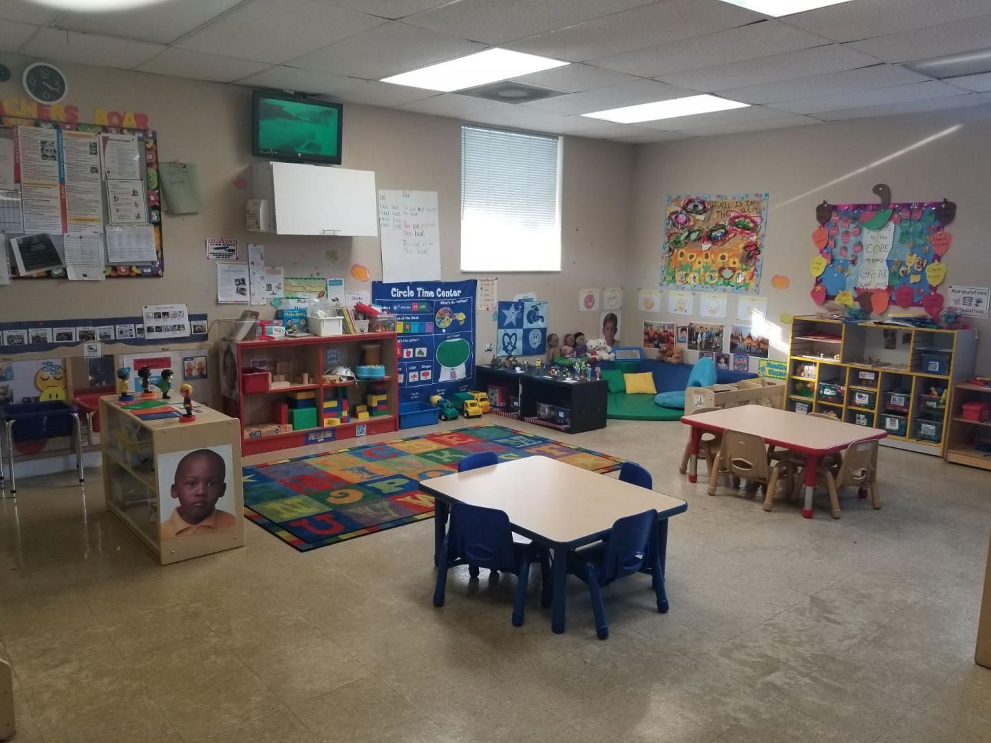 A classroom with tables and chairs and a tv on the wall.