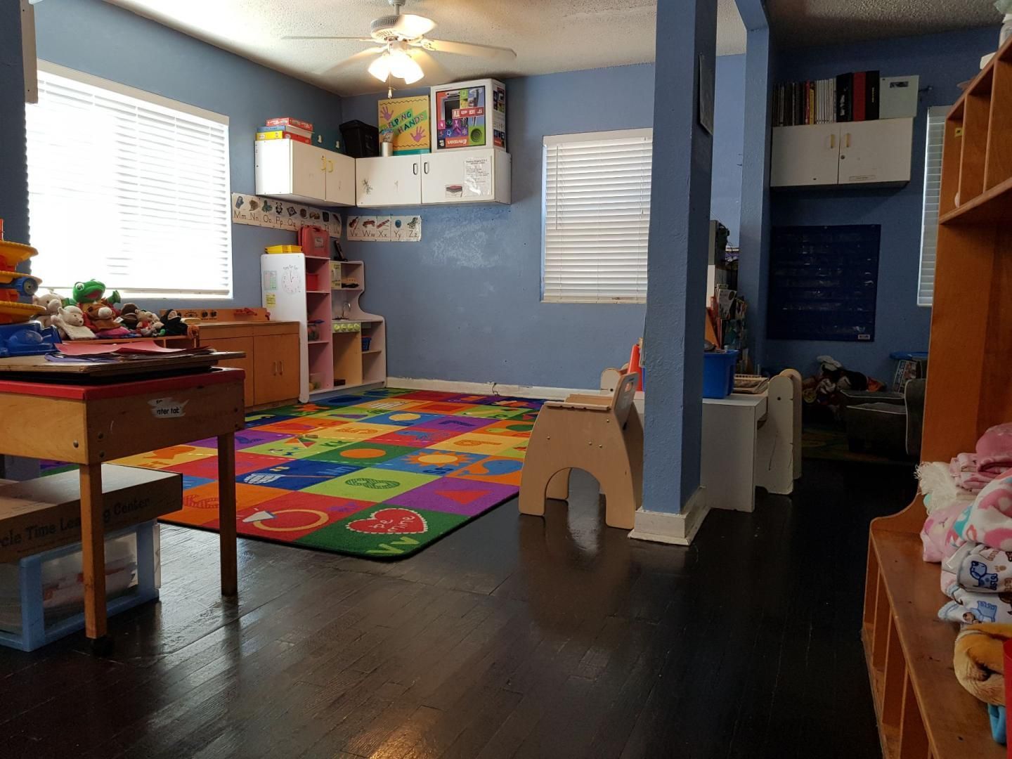 A child 's room with a colorful rug and a ceiling fan.