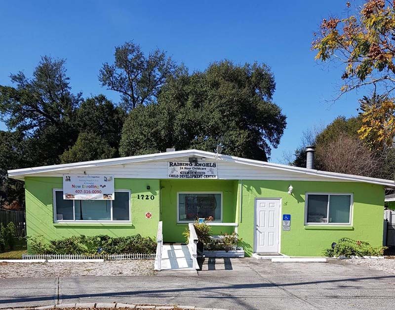 A green house with a white roof and trees in the background