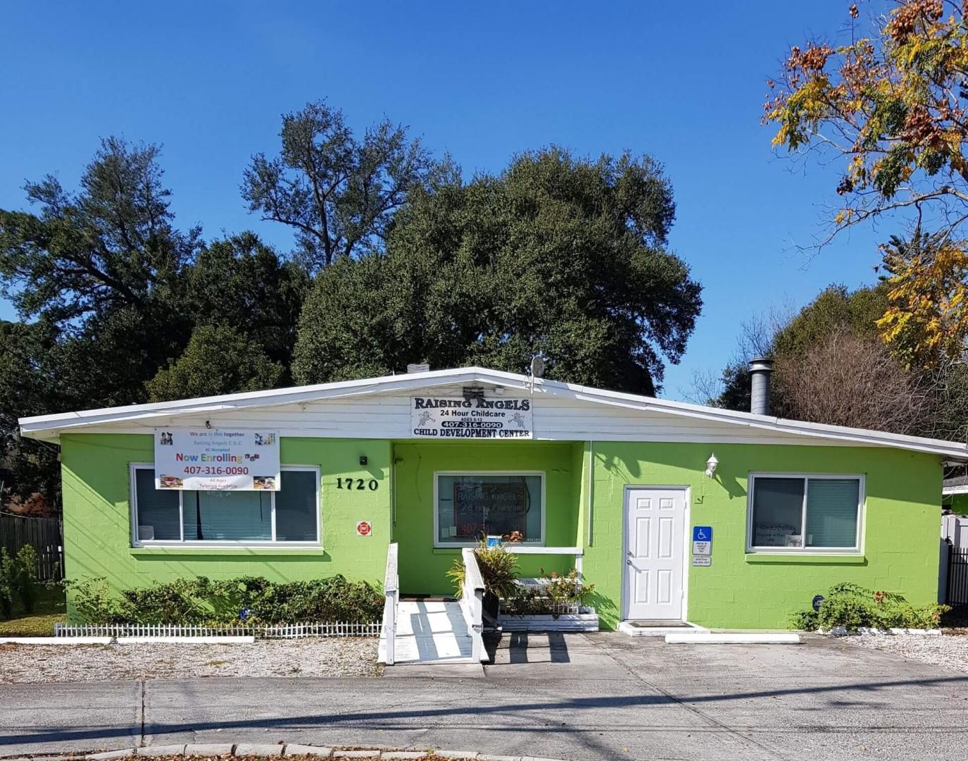 A green house with a white roof and trees in the background