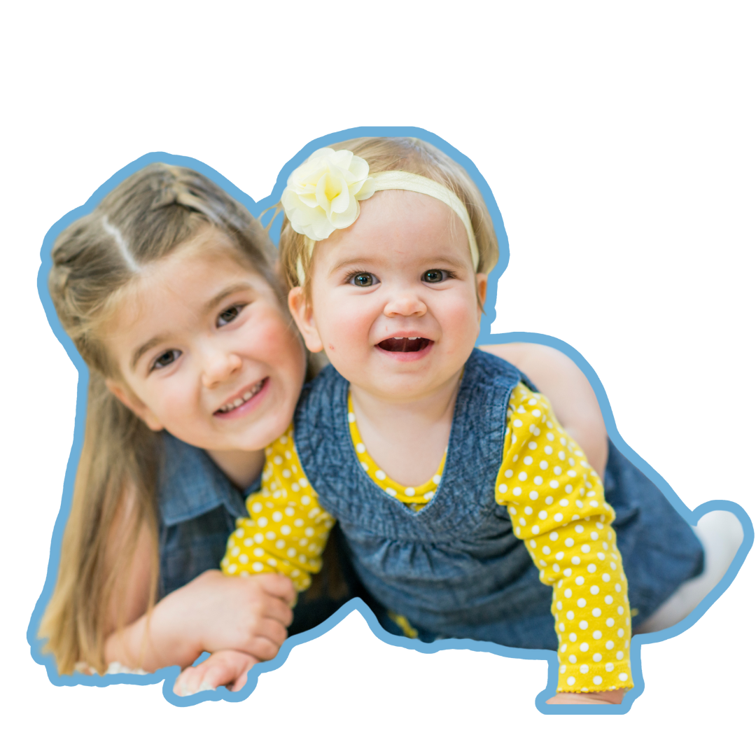 Two little girls are posing for a picture and one has a flower in her hair