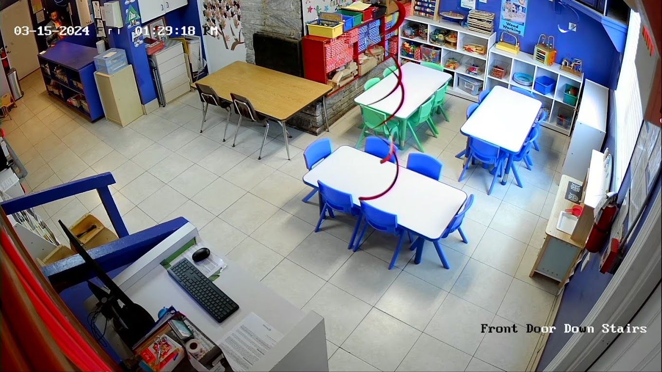 A group of children are sitting on the floor in a classroom with a teacher.