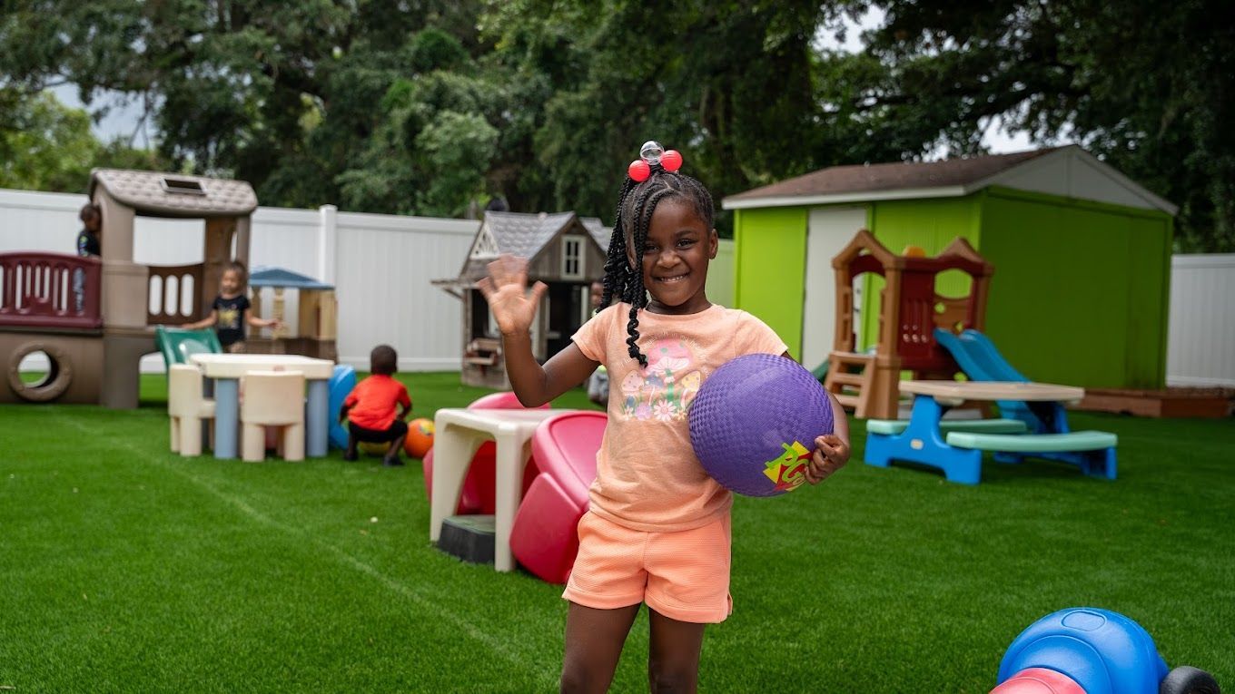 Young girl playing with ball at Raising Angels Orlando playground.