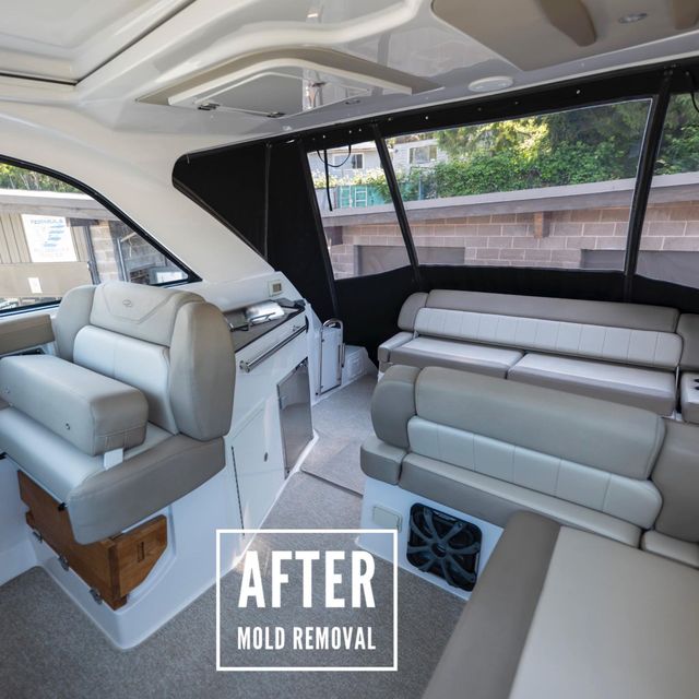 Interior of a boat cabin with seating and a control panel after mold removal. Light and dark gray upholstery.